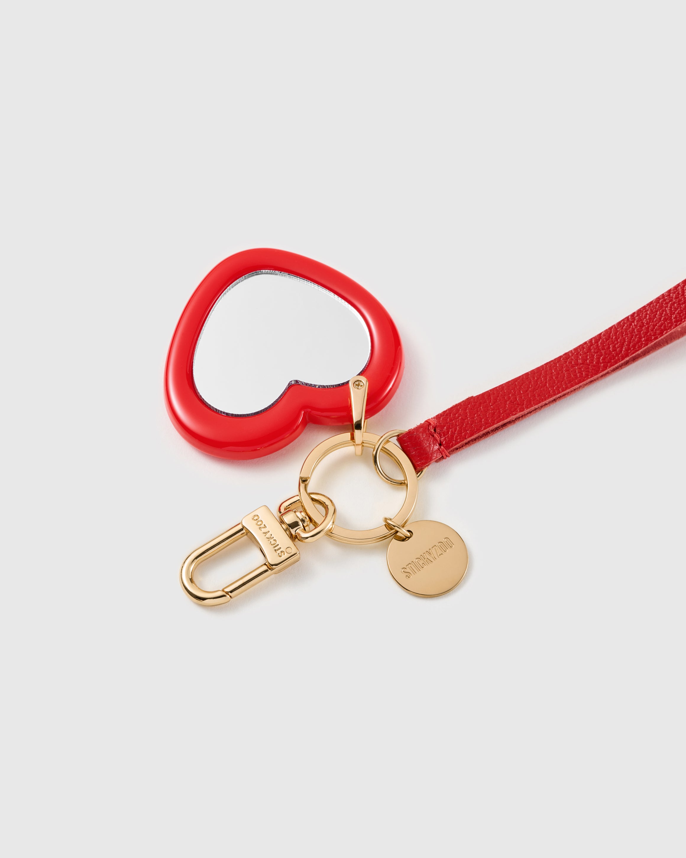 Crimson mirror heart leather phone strap held in hand, ready for a lipstick check before walking in