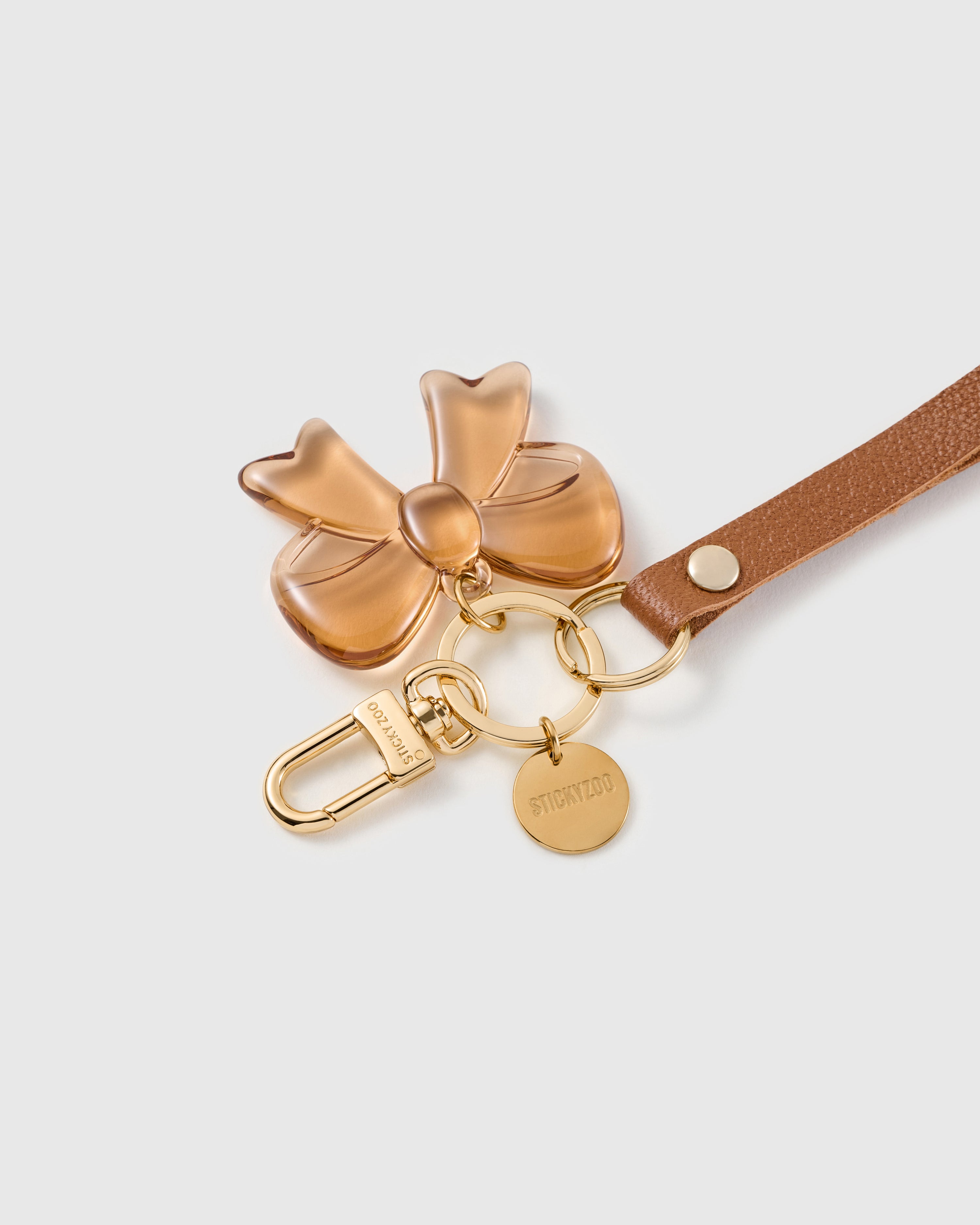 Amber bow leather phone strap clipped to a phone case showing the hands-free wrist loop in use