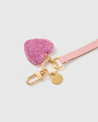 Blush crystal heart leather phone strap clipped to a phone case showing the hands-free wrist loop in use