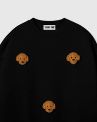 Close-up of hand-stitched plush poodle face on black cotton showing golden curly fur and embroidered eyes