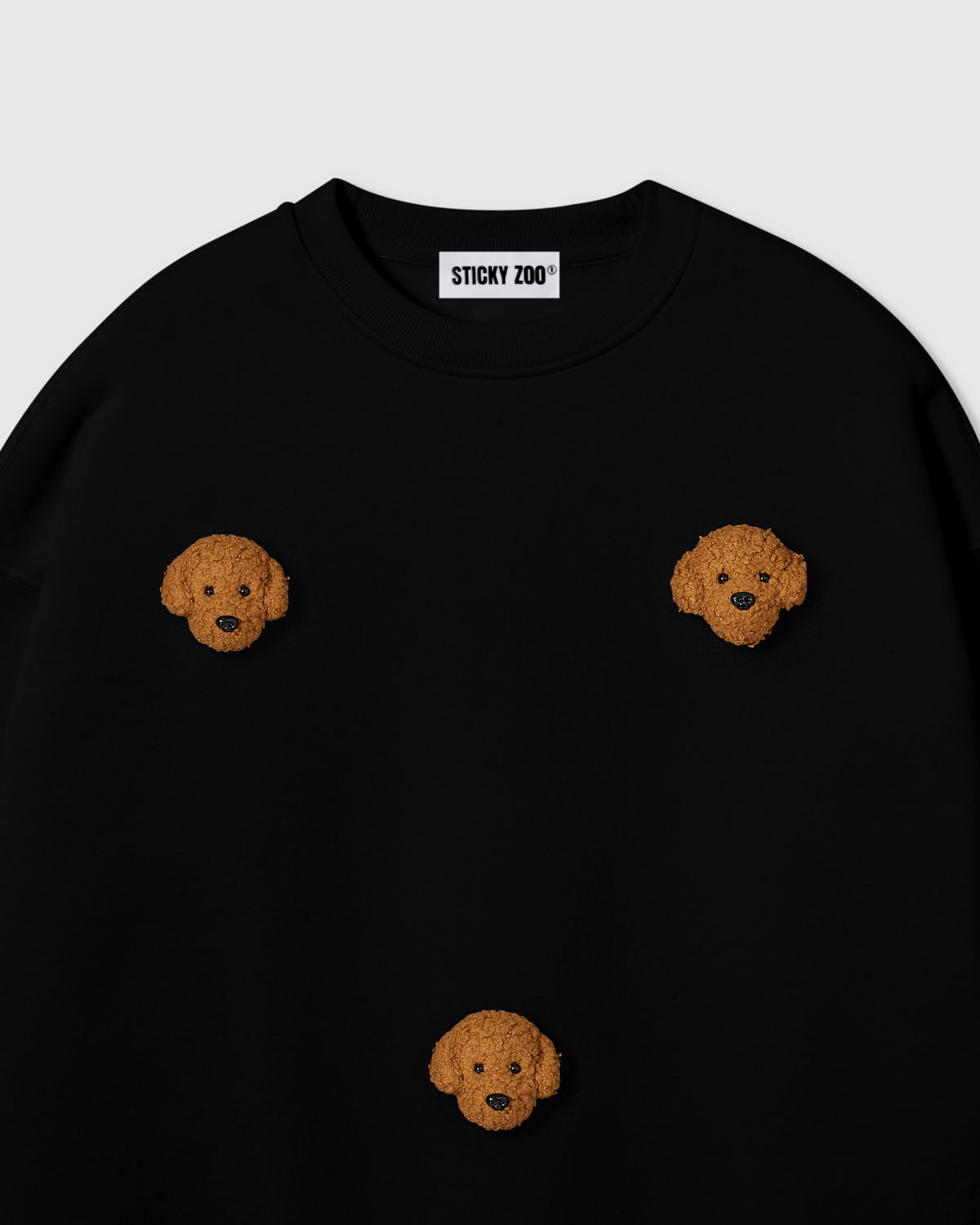 {{Not printed — stitched}} Close-up of hand-stitched plush poodle face on black cotton showing golden curly fur and embroidered eyes