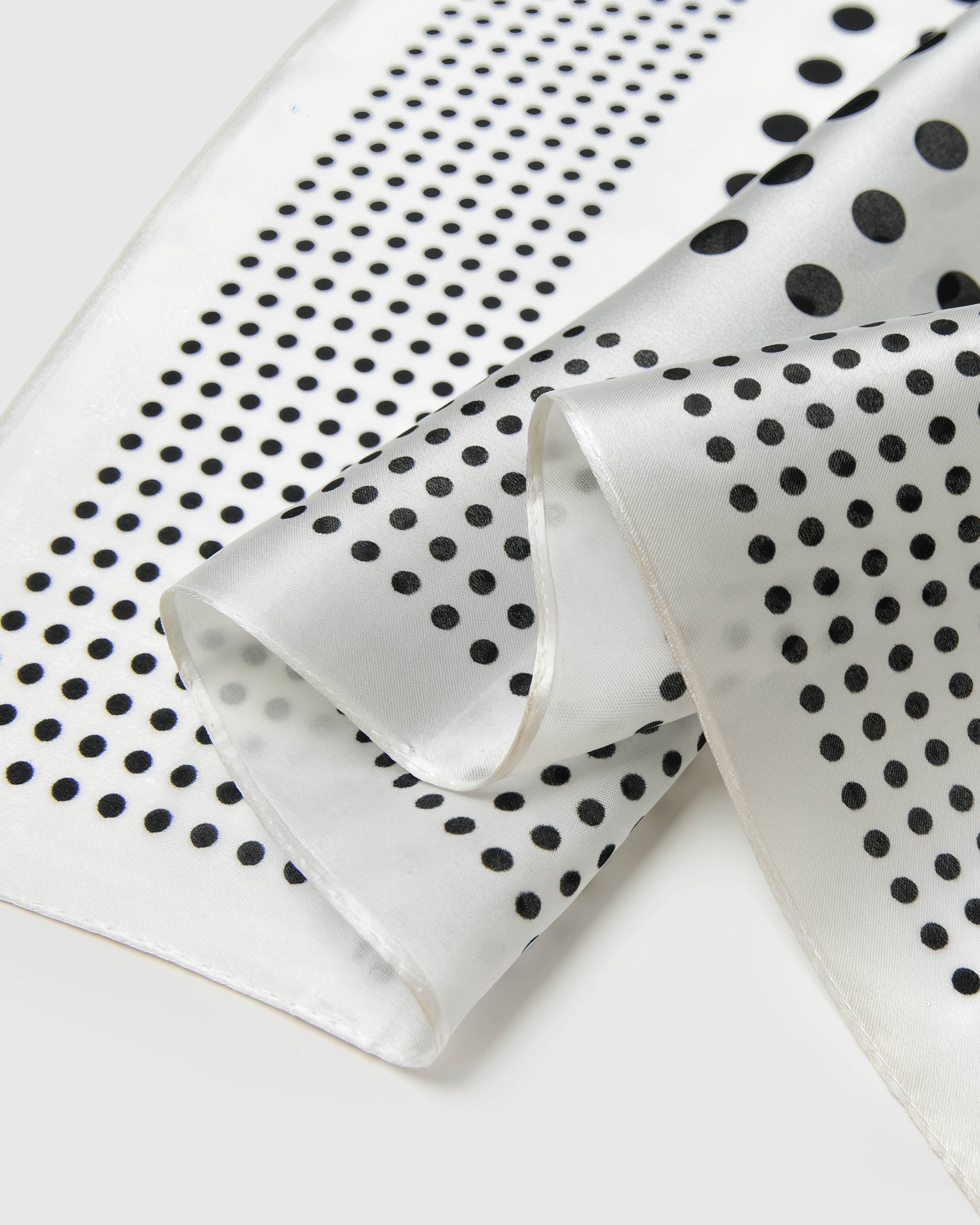 Close-up of the ivory silk edges showing the two-scale black polka dot print in archival ink