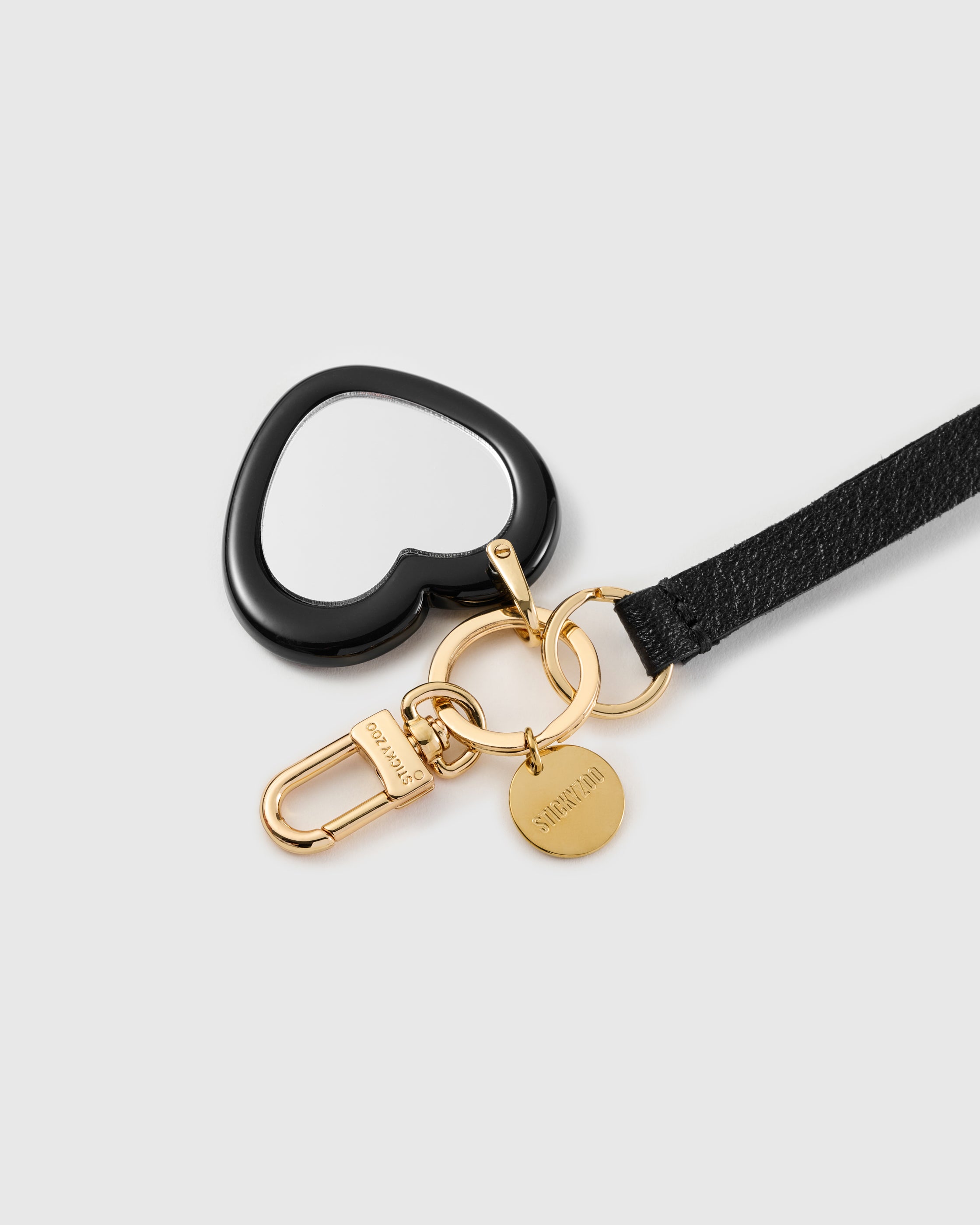 Mirror heart leather phone strap clipped to a phone case showing the hands-free wrist loop in use