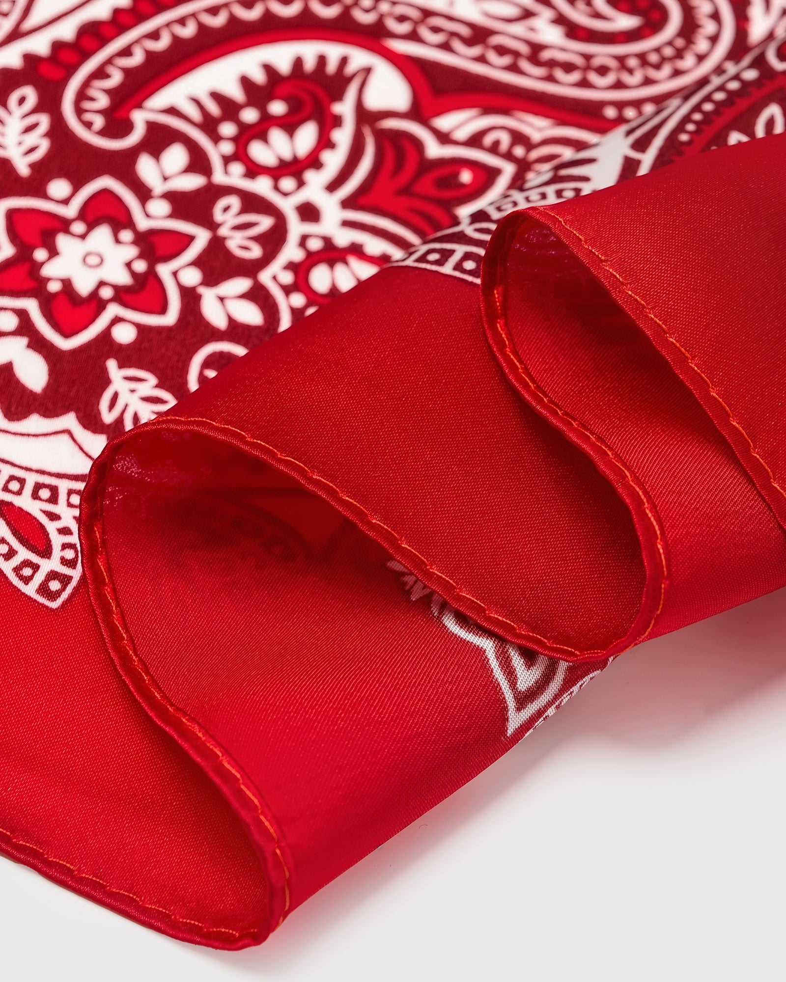 Close-up of the hand-illustrated paisley print along the crimson edge of pure silk