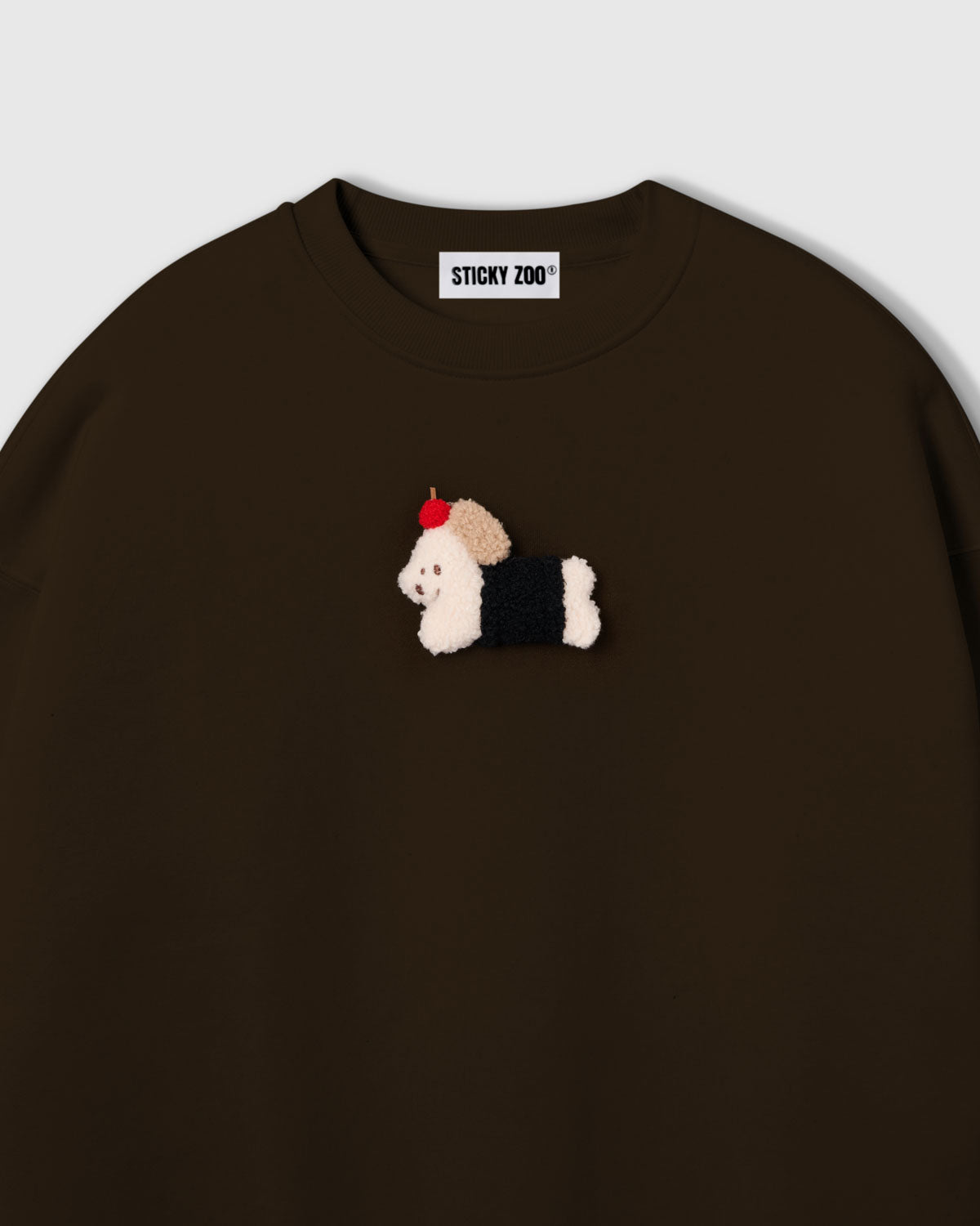 {{Touch it — real 3D plush}} Close-up of plush dachshund in black coat with red apple on brown cotton showing tonal warmth and layered texture