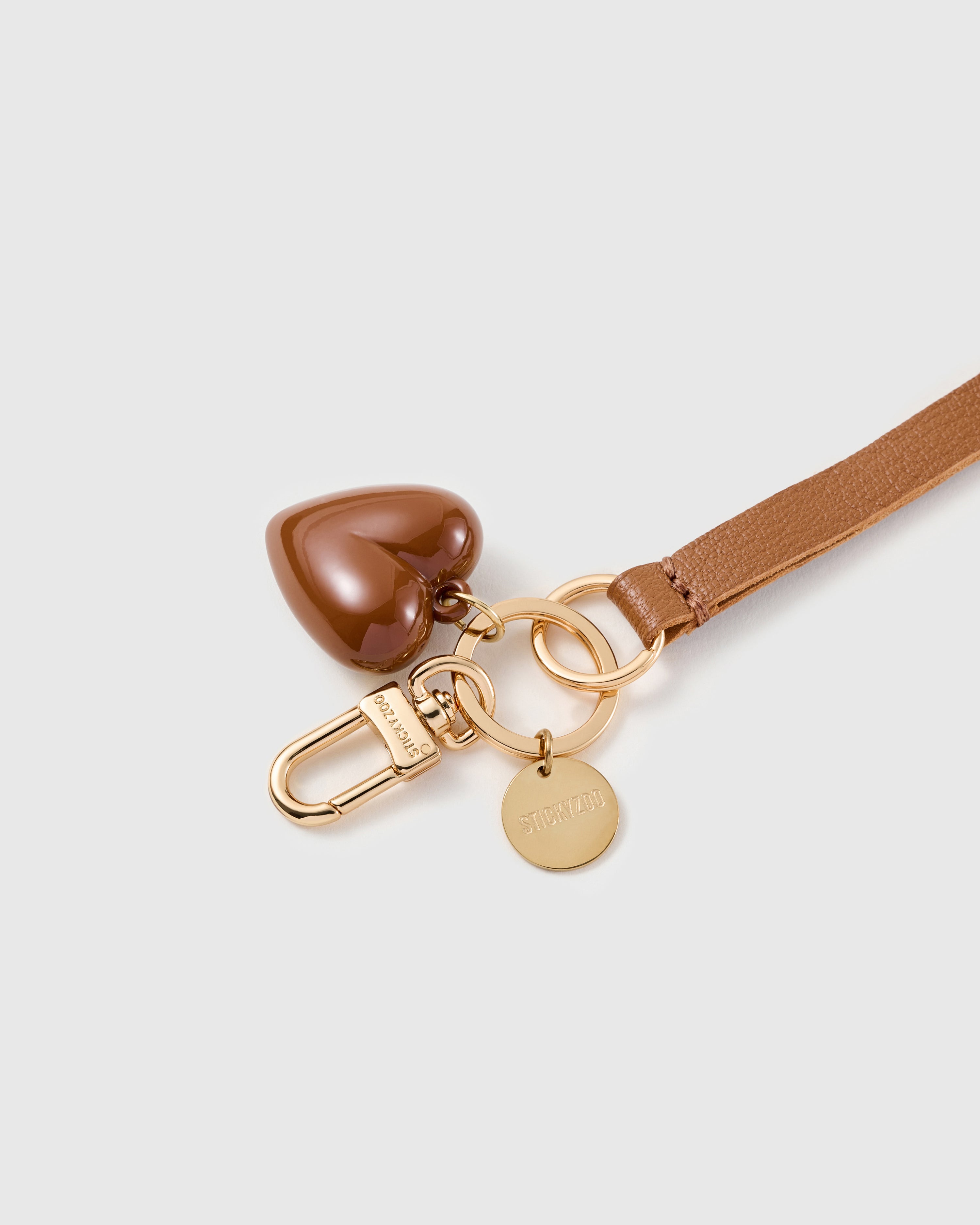 Cocoa puff heart leather phone strap clipped to a phone case showing the hands-free wrist loop in use