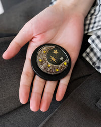Close-up of the bead-embroidered gold crescent moon medallion sealed inside the acrylic-resin grip