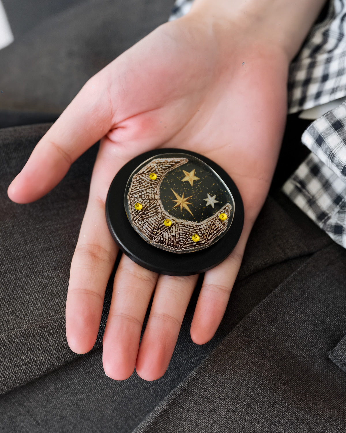 Close-up of the bead-embroidered gold crescent moon medallion sealed inside the acrylic-resin grip