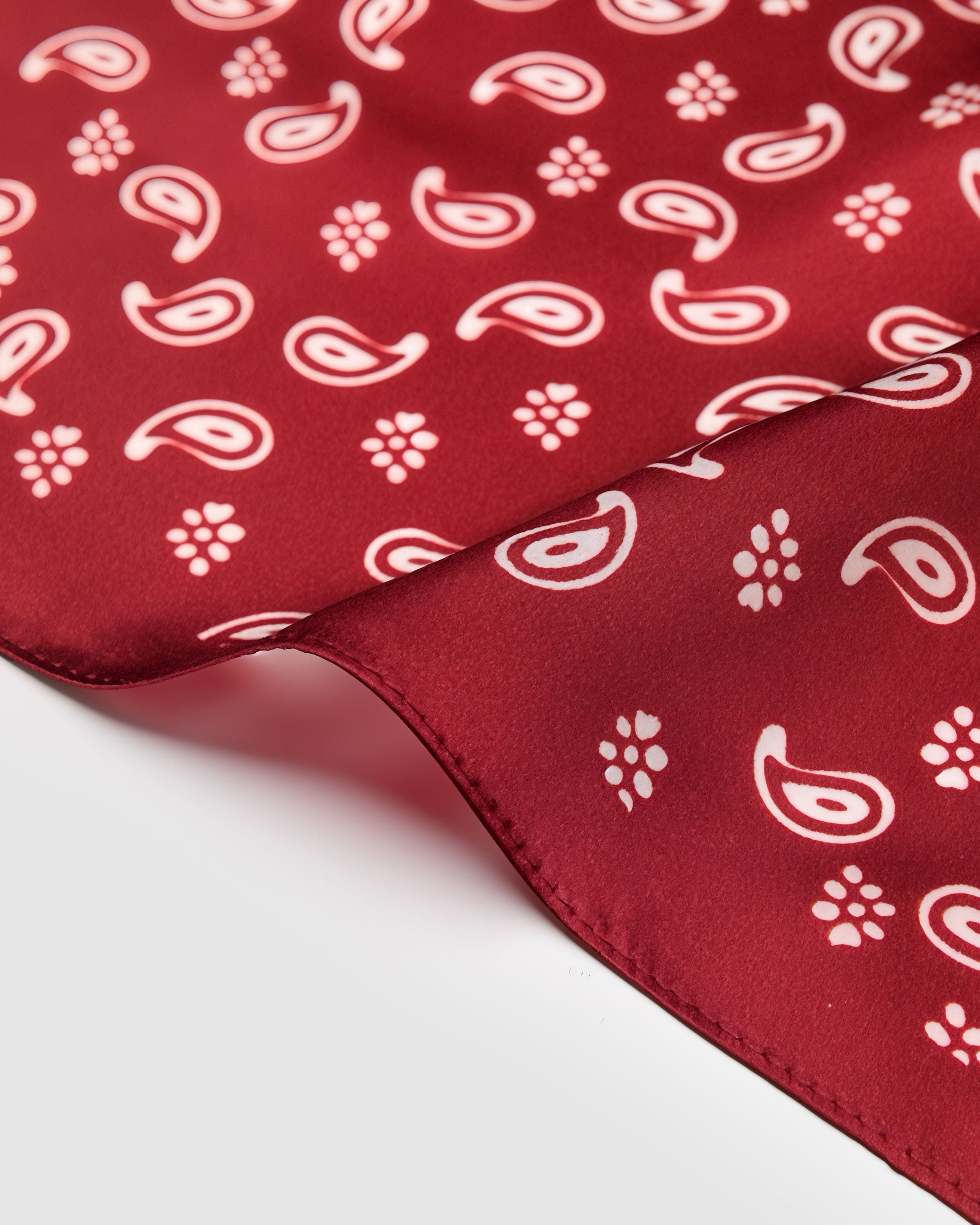 Close-up of the hand-illustrated paisley and small-flower motifs printed in ivory on cardinal silk
```