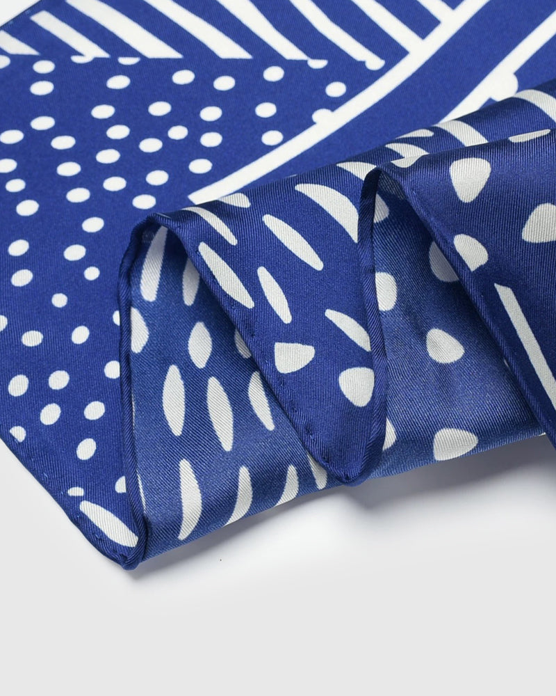 Edge detail of the cobalt silk scarf showing the brushed ivory stripes and the silk hand