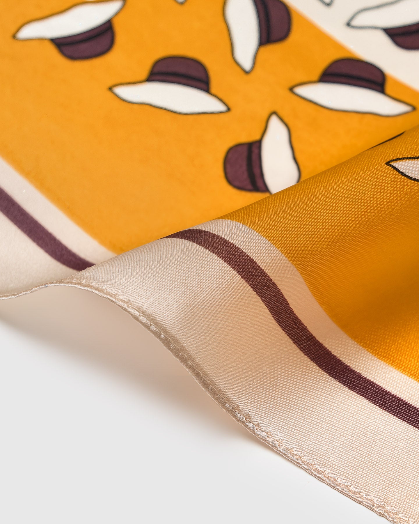 Close-up of the hand-illustrated ivory and plum petals printed in archival ink on the saffron silk field