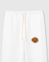 Close-up of plush poodle face applique on white cotton sweatpant showing curly 3D texture and bead eyes