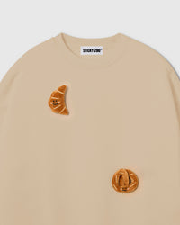 Close-up of crescent plush croissant with smiley face on cream cotton showing warm tonal texture