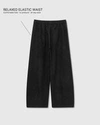 Back view of STICKYZOO Wool Drape Relaxed Pants in black showing elastic waistband and wide-leg construction