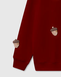 Detail of plush reindeer and tartan acorn appliques on deep red cotton showing dimensional texture