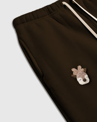 Detail of hand-stitched plush acorn with tartan plaid cap on brown cotton