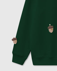 Detail of tartan plaid acorn applique with button center hand-stitched onto green cotton