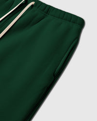 Detail of elastic waistband with cream drawstring on green premium cotton sweatpants showing construction quality