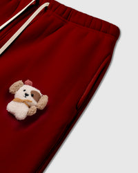 Angled detail of 3D plush puppy on STICKYZOO Cardinal Puppy Sweatpant showing dimensional craft and side pocket