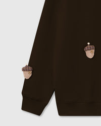 Detail of hand-stitched plush acorn with tartan cap and button center on brown cotton sweatshirt
