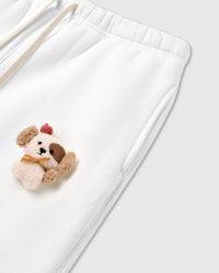 Angled detail of 3D plush puppy on STICKYZOO Cardinal Puppy Sweatpant showing dimensional depth and side pocket
