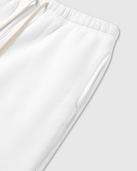 Detail of elastic waistband and cream drawstring on white cotton sweatpants showing fabric weight