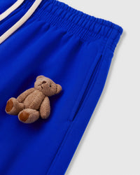 Close-up of plush teddy bear applique at hip pocket area on blue heavyweight fleece showing dimensional hand-sewn construction