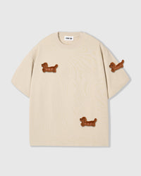 Front flat-lay of STICKYZOO Dash Dachshund T-Shirt in cream colorway with three hand-stitched plush dachshunds