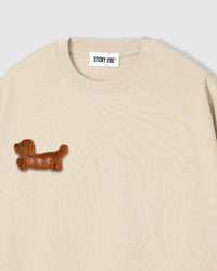 Close-up of plush dachshund applique on cream cotton showing brown fur texture and 3D dimension