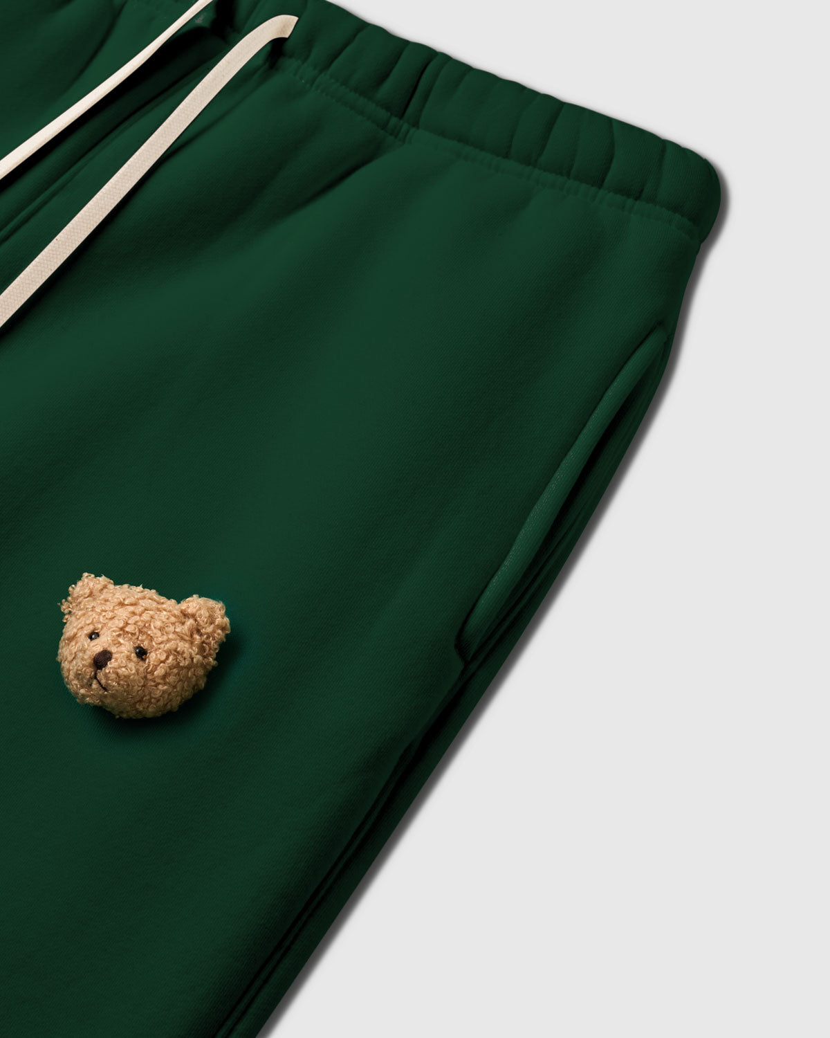Angled detail of hand-stitched plush bear face on STICKYZOO Sticky Bear Sweatpant showing curly fur and dimensional depth