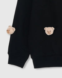 Close-up of plush bear faces at lower front and sleeve cuff with ribbed hem visible