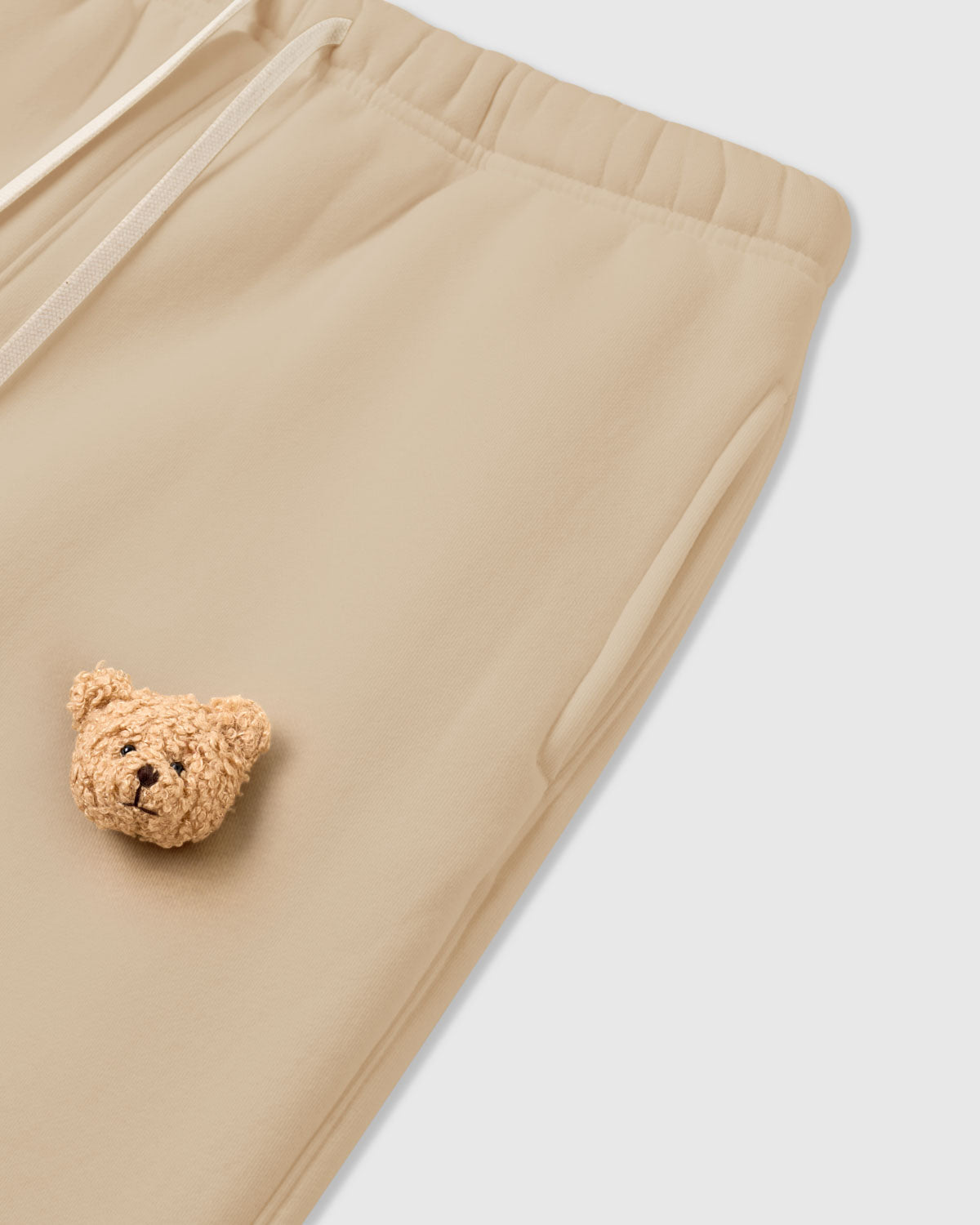 {{Rated 4.9 by thousands}} Detail of bear applique on STICKYZOO cream Sticky Bear Sweatpant showing tonal warmth