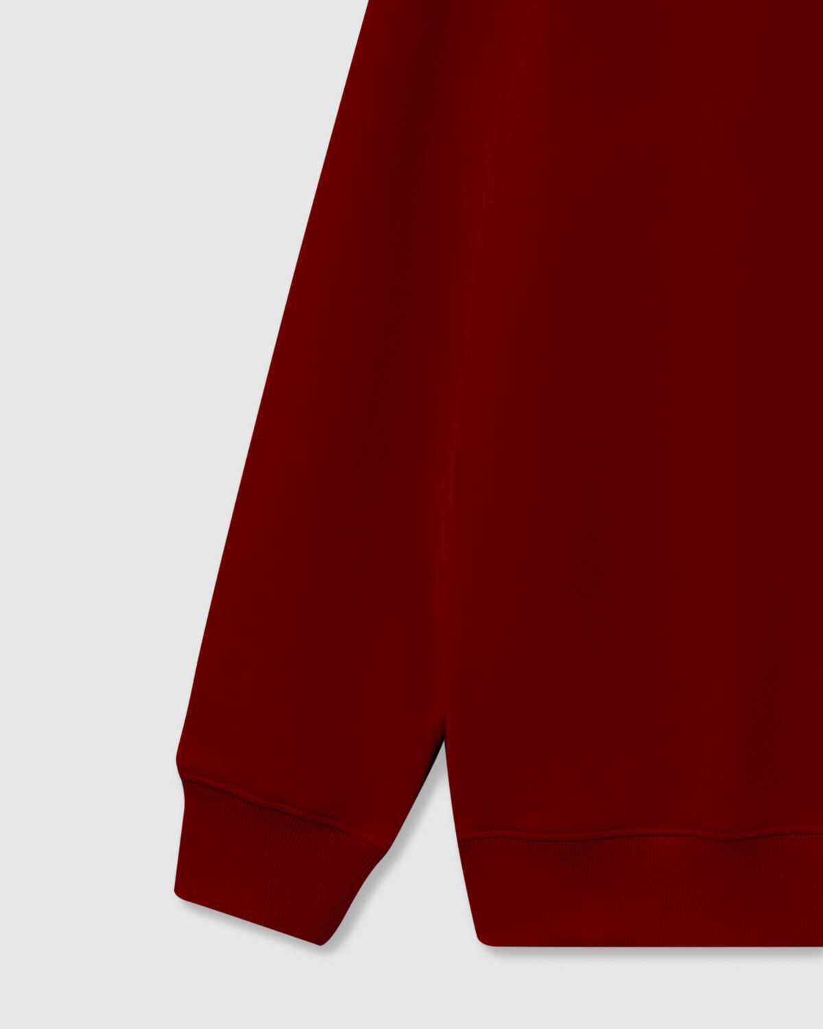 Detail of ribbed cuff and hem on burgundy red premium cotton sweatshirt showing clean construction