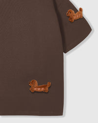 Detail of hand-stitched dachshund on brown tee showing plush fur and embroidered features