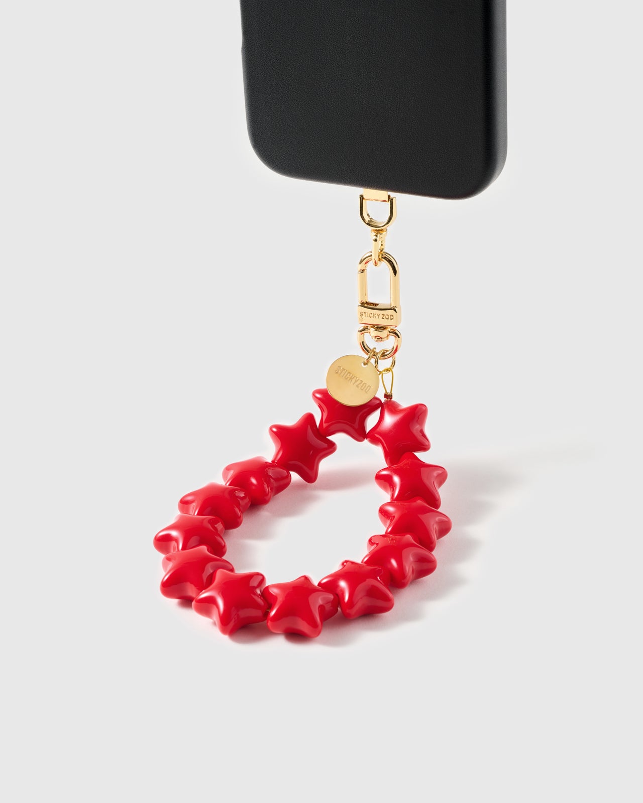 Glossy crimson star bead loop swinging from phone case showing wristlet drape — Loved by Thousands
