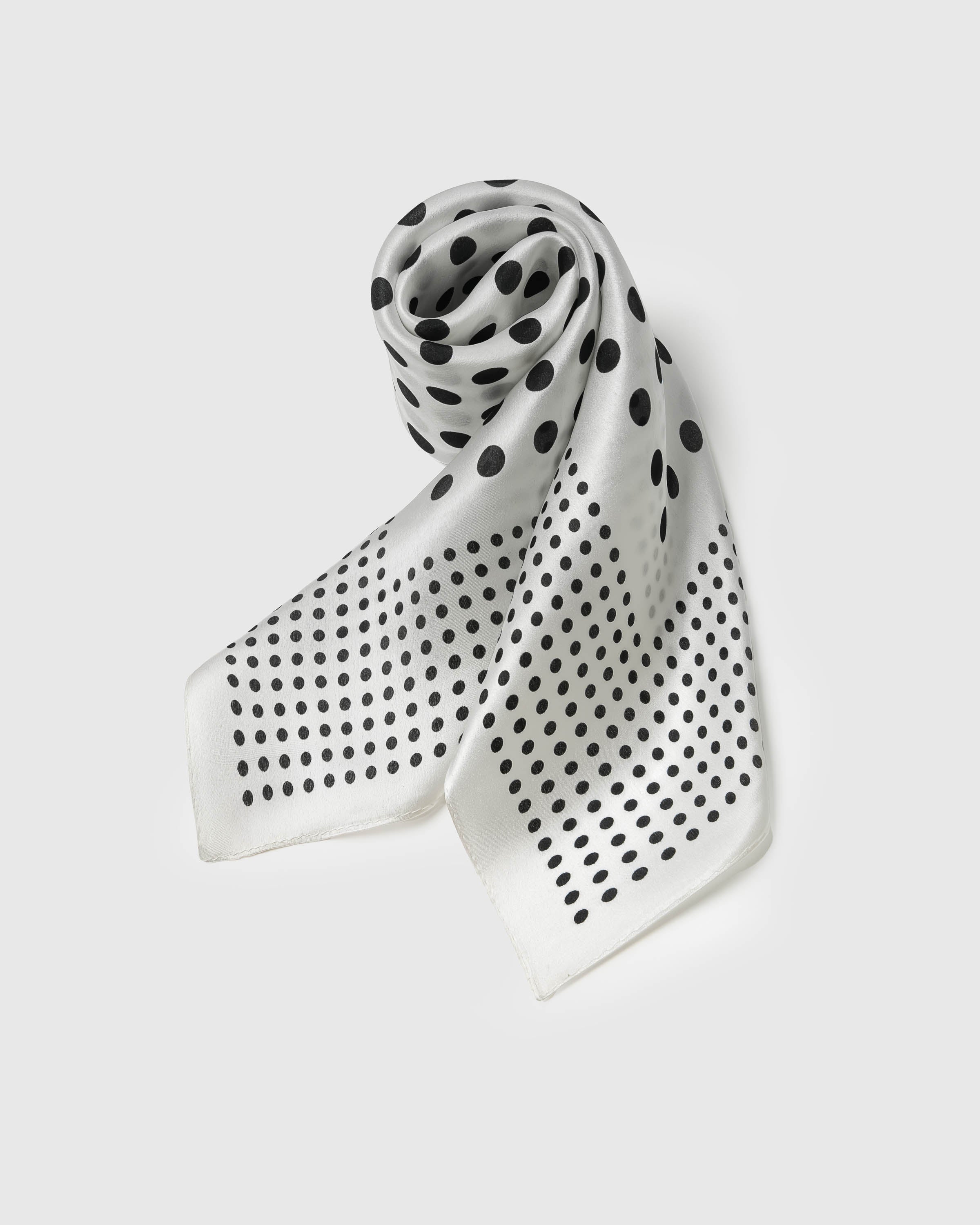Ivory silk dot scarf coiled to show the soft drape and the bright contrast of black polka print on pure silk
```