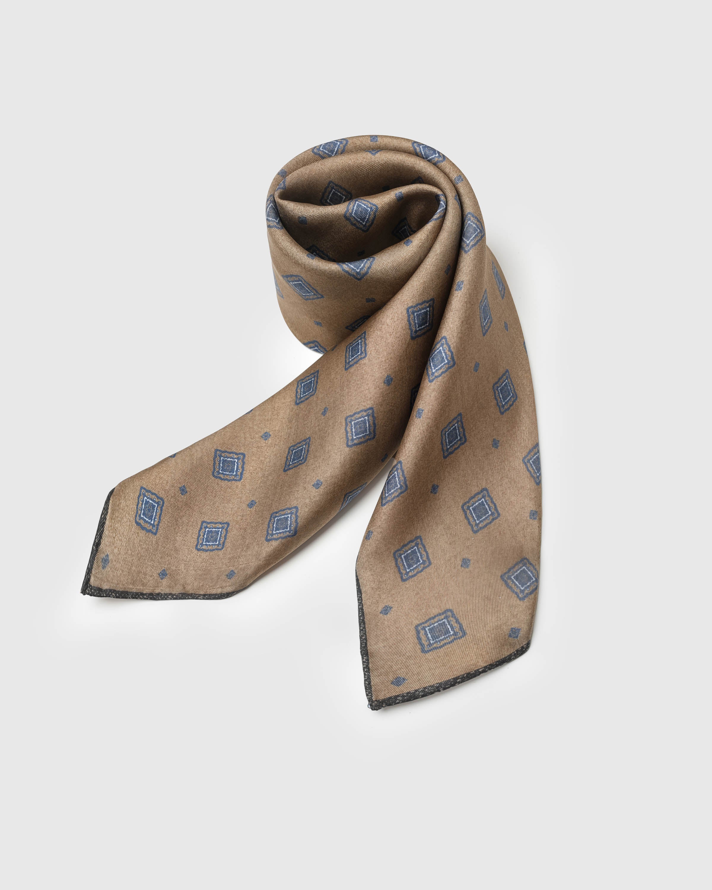 STICKYZOO camel silk scarf coiled to show the soft drape and the dusk blue foulard print
```