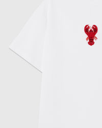 Detail of the raised lobster applique near the shoulder showing sequin tail scales and beaded antennae sewn onto white cotton.