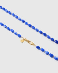 Macro close-up of polished cobalt resin nugget beads and gold-plated clasp on a handmade STICKYZOO strap