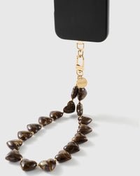 Tortoiseshell Heart strap on a black phone, showing the gold-tone STICKYZOO connector, engraved disc and glossy amber marbled heart beads.