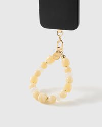 Buttermilk beaded wrist strap clipped to a black phone case for hands-free carry