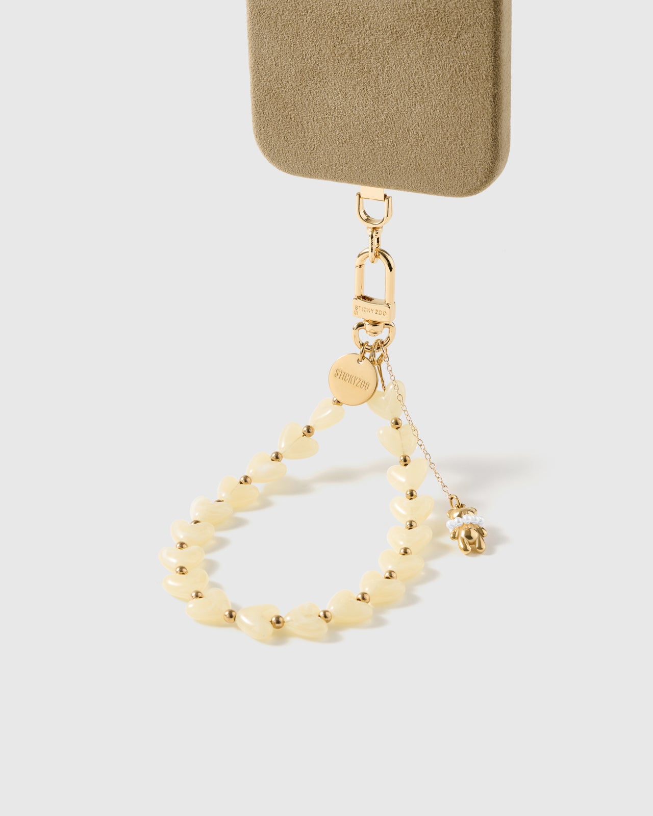 ivory teddy heart phone strap clipped to a black phone case — hands-free wrist carry. Rated 4.9 stars.