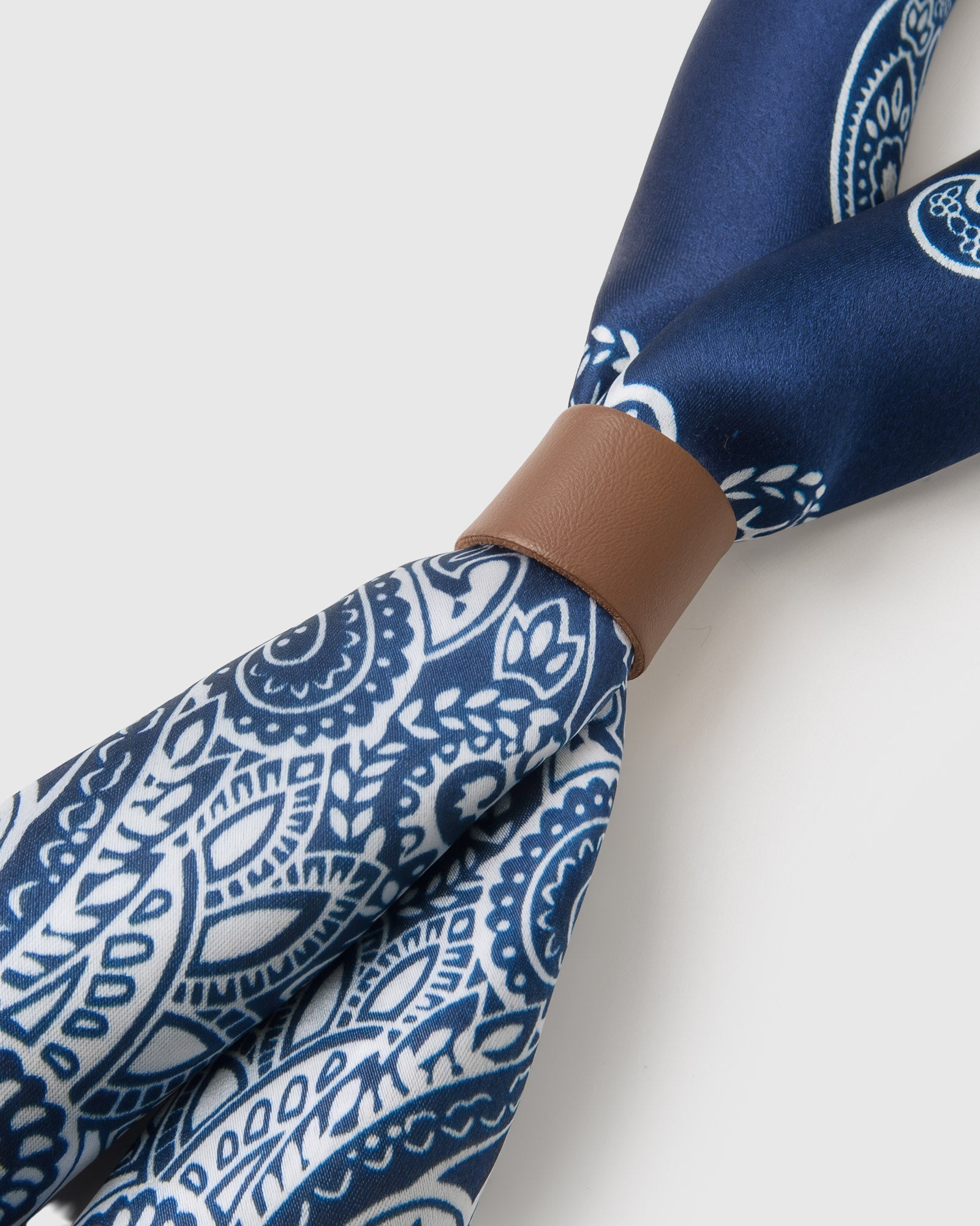 Corner detail of the porcelain paisley silk scarf showing the ivory wreath frame and silk hand
```