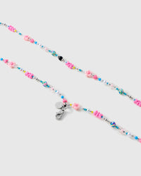 Close-up of molded pink flower beads, small hearts, white faux-pearl rounds and turquoise seed beads beside a silver-tone lobster clasp.