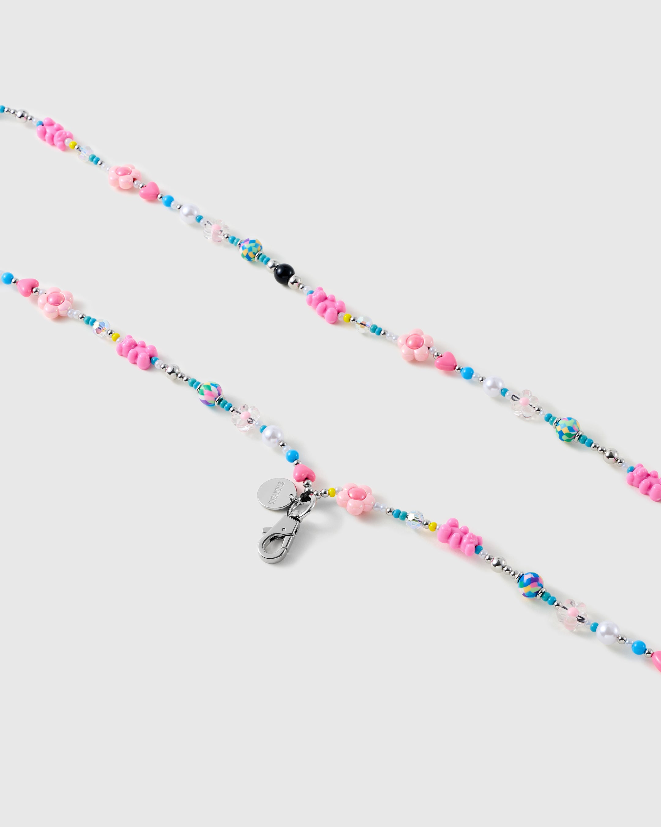 Close-up of molded pink flower beads, small hearts, white faux-pearl rounds and turquoise seed beads beside a silver-tone lobster clasp.