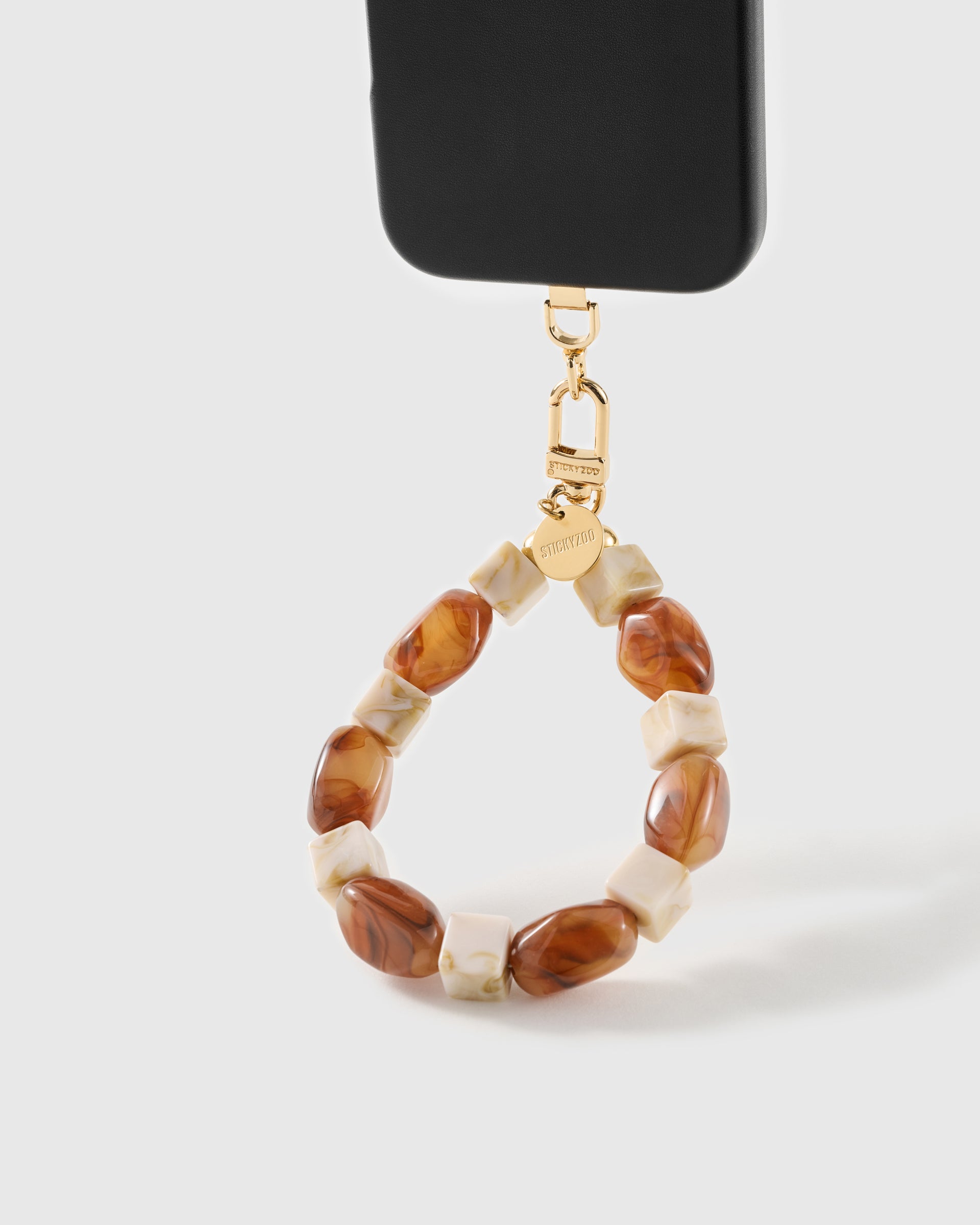Cognac marbled bead wrist strap clipped to a black phone case for hands-free carry