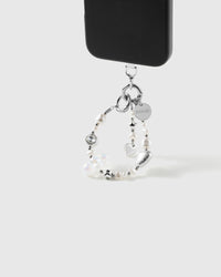 White pearl and silver-heart beaded wrist strap hanging from a black phone by a silver-tone hook and engraved STICKYZOO disc