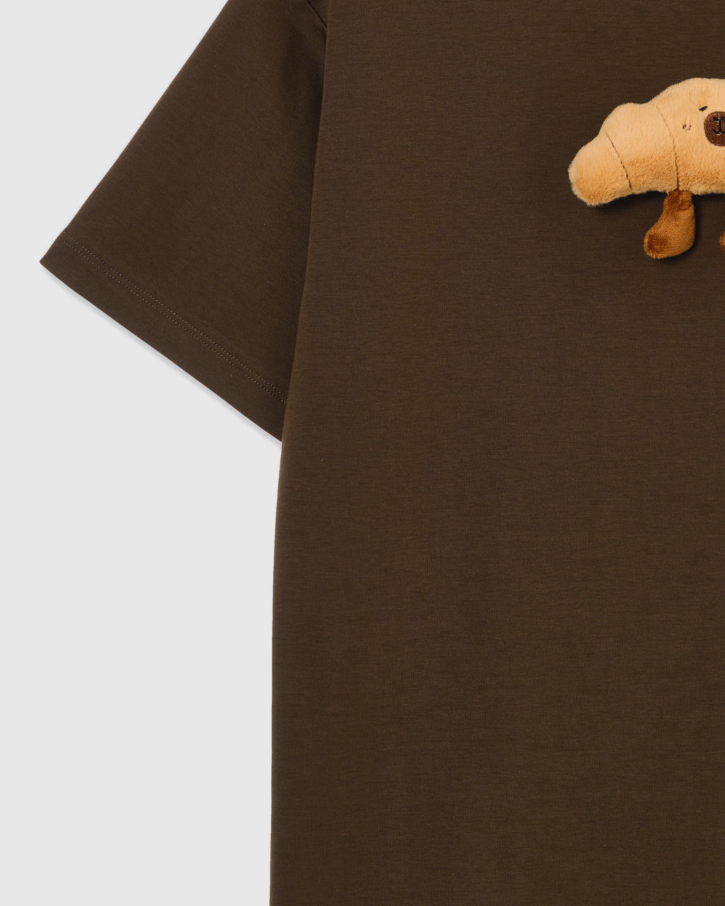 Detail of sleeve and side on STICKYZOO brown Runaway Croissant T-Shirt showing boxy construction