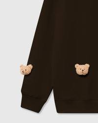 Close-up of plush bear faces on brown cotton showing dimensional texture and embroidered features