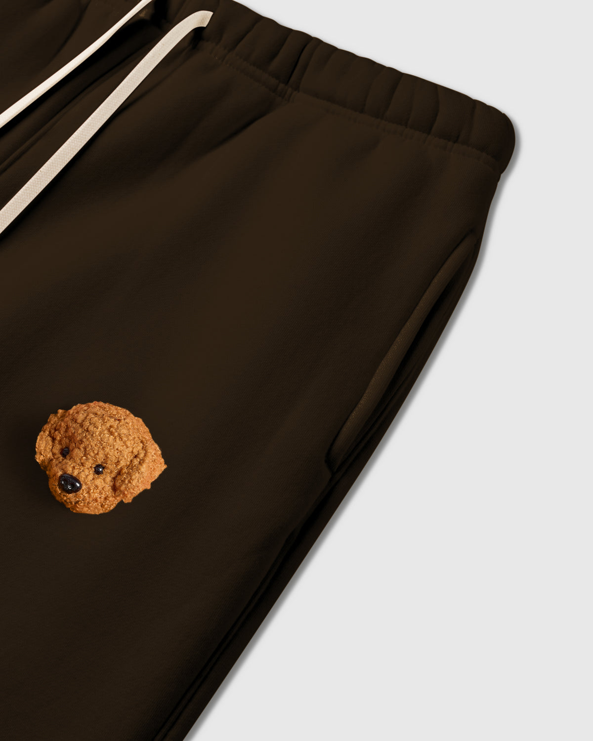 Close-up of plush poodle applique near pocket on dark brown 350gsm cotton showing 3D texture